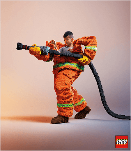 Esta é uma foto de um anúncio da LEGO que mostra um jovem asiático dentro de um uniforme de bombeiro feito de LEGOs. O uniforme é laranja com uma faixa verde neon em torno dos punhos do casaco e das calças. O bombeiro está parado com um pé para trás e segurando uma mangueira, também feita de legos. A cabeça do menino aparece por cima do uniforme, que é muito maior do que ele e pára em volta dos ombros. A foto foi tirada contra um fundo neutro liso. O logotipo da LEGO aparece em uma caixa vermelha no canto inferior direito. Talia Wolf afirma que a LEGO é um ótimo exemplo de marca que usa emoção na publicidade.