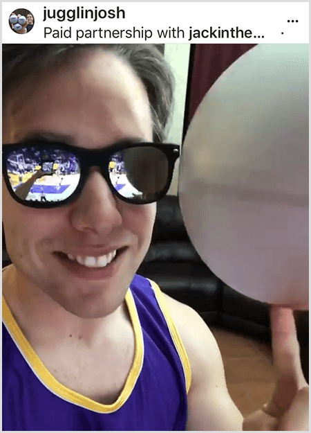 Josh Horton posta uma foto para uma campanha com Jack in the Box e LA Lakers. Josh usa óculos escuros espelhados e uma camisa do Lakers e está sorrindo para a câmera enquanto gira uma bola.